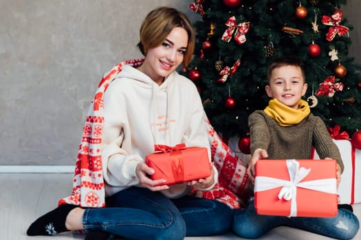 Mom with son at christmas tree with gifts new year