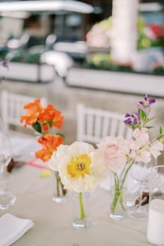 Bright flowers stand in glass vases on a festive table . High quality photo