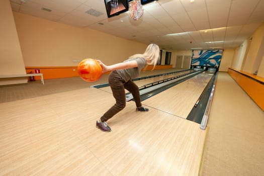 A girl throws a ball while playing bowling. High quality photo