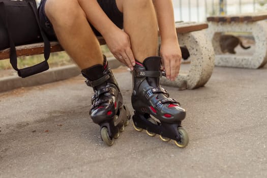 Legs of young man putting on roller skates in the park.