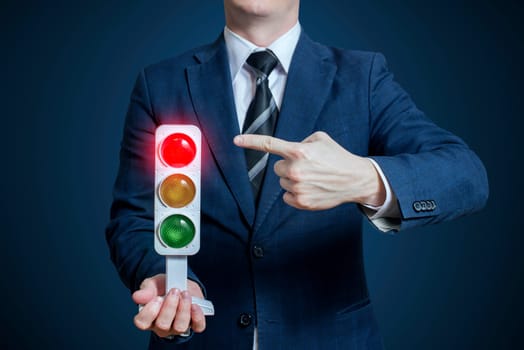 Businessman holding a traffic light with red light on. Business concept