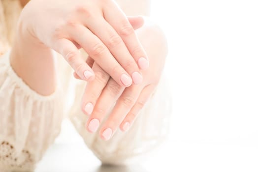 Womans hands with beautiful manicure on white background. Closeup shot of womans hands in a nail salon.