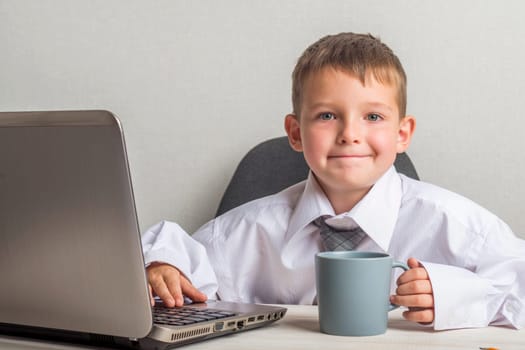 Little boss in the office. A kid businessman with glasses with laptop working in office.