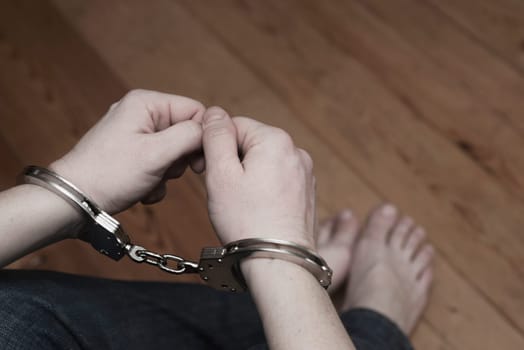 Man detained in handcuffs. Prisoner or arrested man in handcuffs. Male hands in handcuffs. Criminal law.