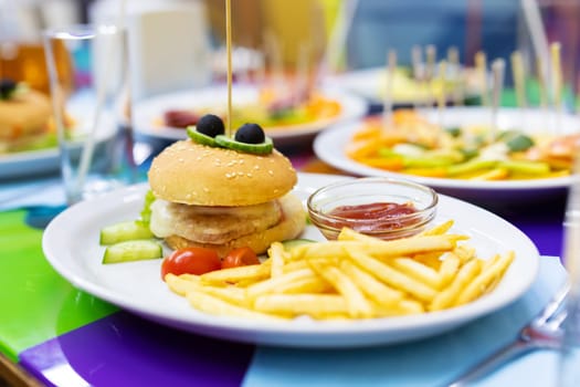 Mini burgers and fried potatoes with sauce on white plate. Kids meal. Kids menu of the restaurant.