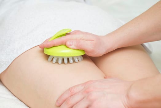Masseur makes anticellulite massage young woman using massager. Massage with massager to prevent cellulite.