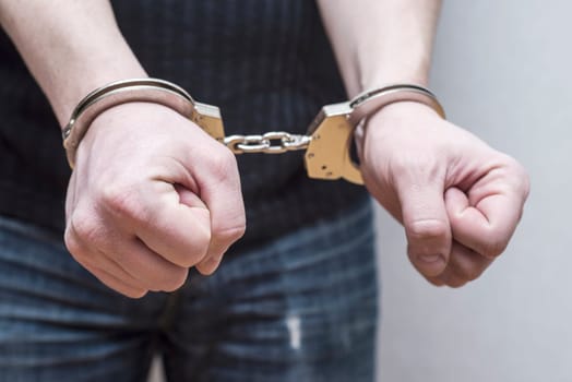 Man detained in handcuffs. Prisoner or arrested man in handcuffs. Male hands in handcuffs. Criminal law.