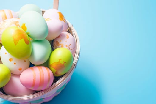 Easter basket filled with painted Easter Eggs over a blue background. Colorful painted easter eggs in basket on blue background.