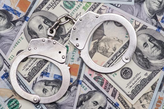 Handcuffs on money background. Dollar bills, money cash corruption, dirty money financial crime and metal police handcuffs.