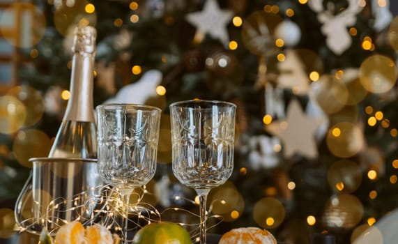 Champagne glasses, New Year decor. New Year's festive setting, family holidays.Two glasses of champagne are on the table against the background of New Year's decorated tree