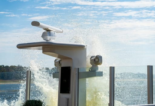 Spray and wave from passing freight barge creates splash onto deck of a modern Mississippi river cruise boat