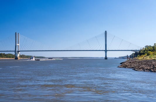 Modern cable-stayed suspension bridge, the Jesse Brent Memorial bridge across the Mississippi river near Greenville with river barge