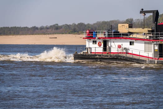Detail of the stern of a pusher boat or tugboat churning the Mississippi river in Missouri with sand bar