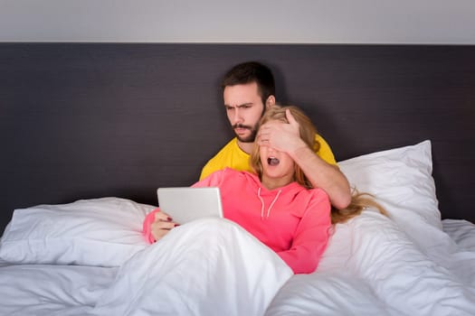 Young Sweet Couple on Bed Watching Something on Tablet Gadget. Concept about technology and people