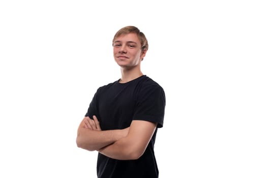 European blond teenager boy wearing a black T-shirt is proud of himself.