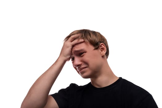 Excited teenager guy in a black T-shirt holding his head.