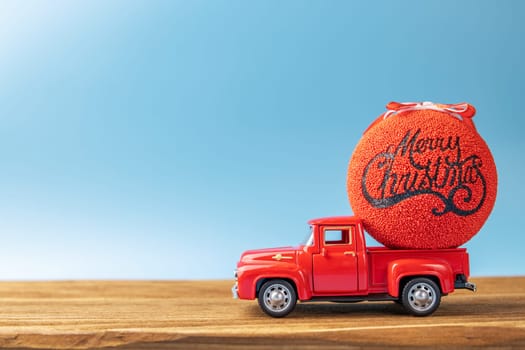 Christmas red retro car with a Christmas ball on a blue background. Space for text. Greeting card Merry Christmas and Happy New year.