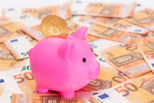 Pink Piggy Bank with Bitcoin Coin on the Fifty Euro Banknotes. Small Money Box for Cash and Coins. Money Saving Concept
