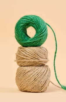 Skein of green and brown thread on a beige background