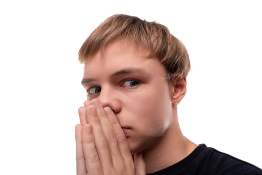 Blonde teenager boy is surprised and looks suspiciously to the side.