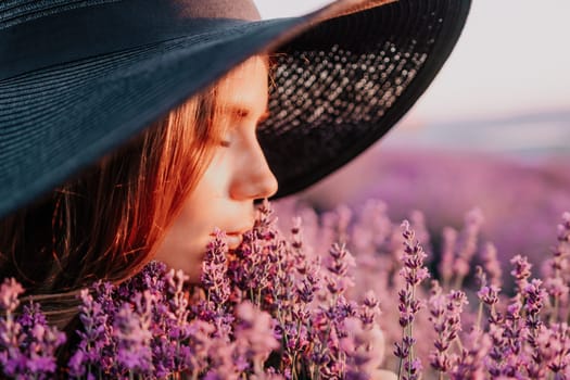 Close up portrait of young beautiful woman in a white dress and a hat is walking in the lavender field and smelling lavender bouquet.