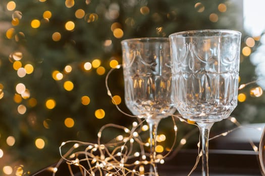 Champagne glasses, New Year decor. New Year's festive setting, family holidays.Two glasses of champagne are on the table against the background of New Year's decorated tree