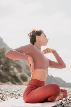 Young woman with long hair in white swimsuit and boho style braclets practicing outdoors on yoga mat by the sea on a sunset. Women's yoga fitness routine. Healthy lifestyle, harmony and meditation