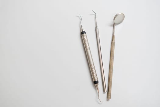 Dental tools, mirror, explorer, hook on the white background with copy space.