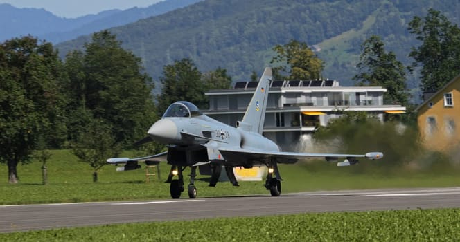 Mollis, Switzerland, August 19, 2023: A Luftwaffe Eurofighter Typhoon takes off with afterburners against a lush landscape.