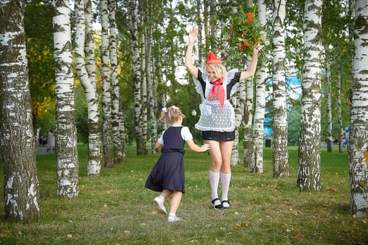 Young and adult schoolgirl on September 1, mother and daughter having fun and joy. Generations of schoolchildren of USSR and Russia. Female pioneer in red tie and October girl in modern uniform