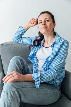 Beautiful brunette woman posing in armchair in bright room