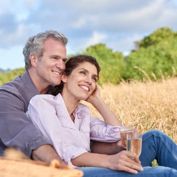 Senior couple, relax and picnic in park, grass and drink in nature for a date in retirement with love or care. Mature, woman and man in field in summer, holiday or vacation with freedom and wine.
