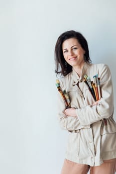 Brunette woman with art brushes on white
