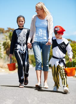 Mother, children and holding hands with Halloween costume, fun and playing with joy, cheerful or love. Outdoor, mama or kids with fantasy outfit, happiness or walking with a smile or family in street.