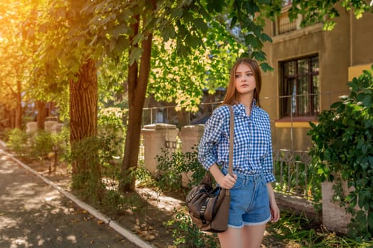 Portrait of a beautiful young woman on the streets of the beautiful city with foliage, shrubs, trees, sunny summer day.