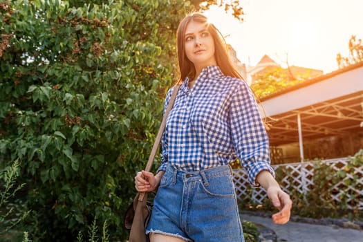 Portrait of a beautiful young woman on the streets of the beautiful city with foliage, shrubs, sunny summer day.