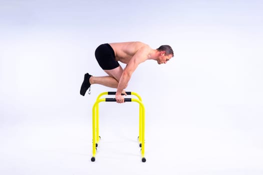 Male gymnast performing handstand on a parallel bars, studio shot