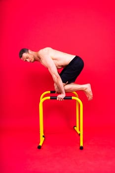 Male gymnast performing handstand on a parallel bars, studio shot