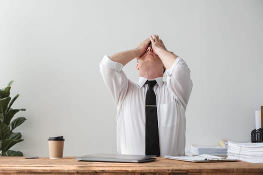 Unhappy young businessman feeling bored and stressed at work looking at laptop with hopeless expression while sitting in office.