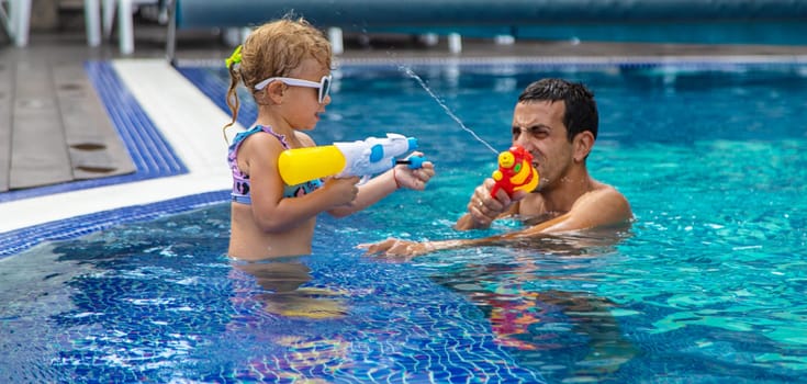 A child and his father play with a water pistol in the water. Selective focus. Kid.