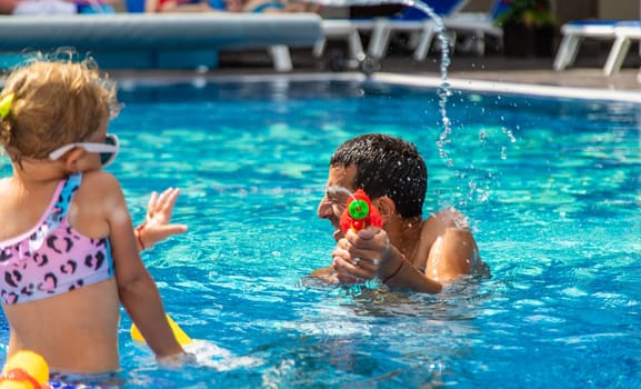 A child and his father play with a water pistol in the water. Selective focus. Kid.