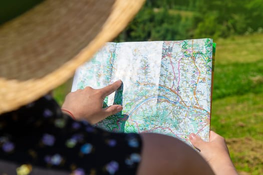 A woman in the mountains looks at a map. Selective focus. Nature.