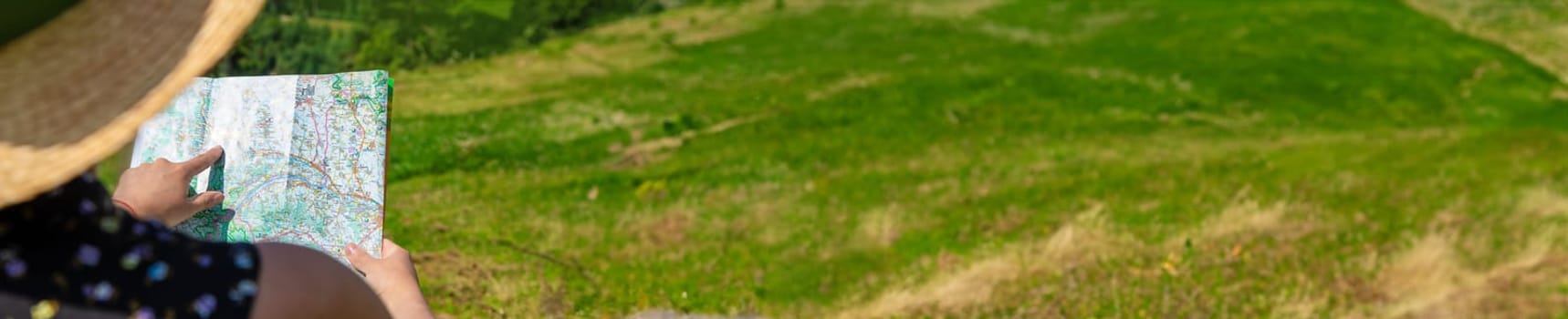 A woman in the mountains looks at a map. Selective focus. Nature.