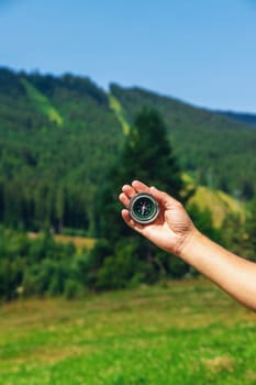 A man in the mountains holds a compass in her hands. Selective focus. Nature.
