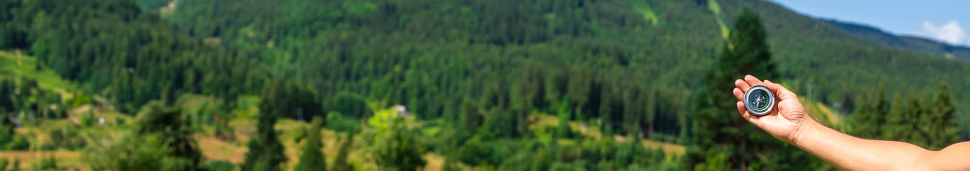 A man in the mountains holds a compass in her hands. Selective focus. Nature.