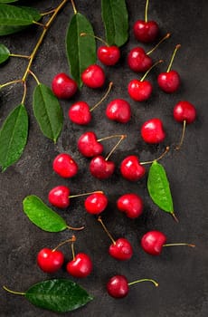 Ripe sweet cherry berry with leaves on a black wooden board