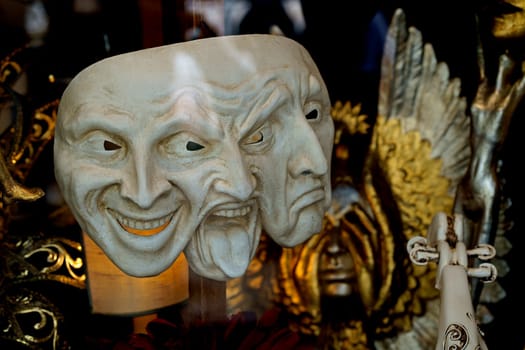 venetian mask expresses joy, irritation and sadness standing in a store window on a black