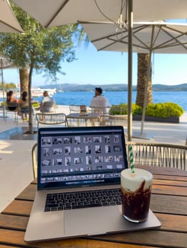 Milkshake stands on a laptop on a table in a street cafe. High quality photo