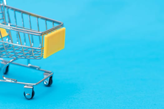 Empty Yellow Shopping Cart on Blue Background. Shopping, Trade and Market Concept