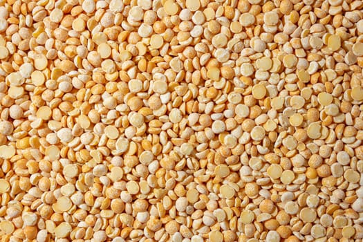 Uncooked Polished Split Peas Background. A Culinary Canvas of Dry Yellow Peas, Creating a Lively and Textured Background for Gourmet Cooking. Scattered Raw Polished Peas. Healthy Eating Ingredients